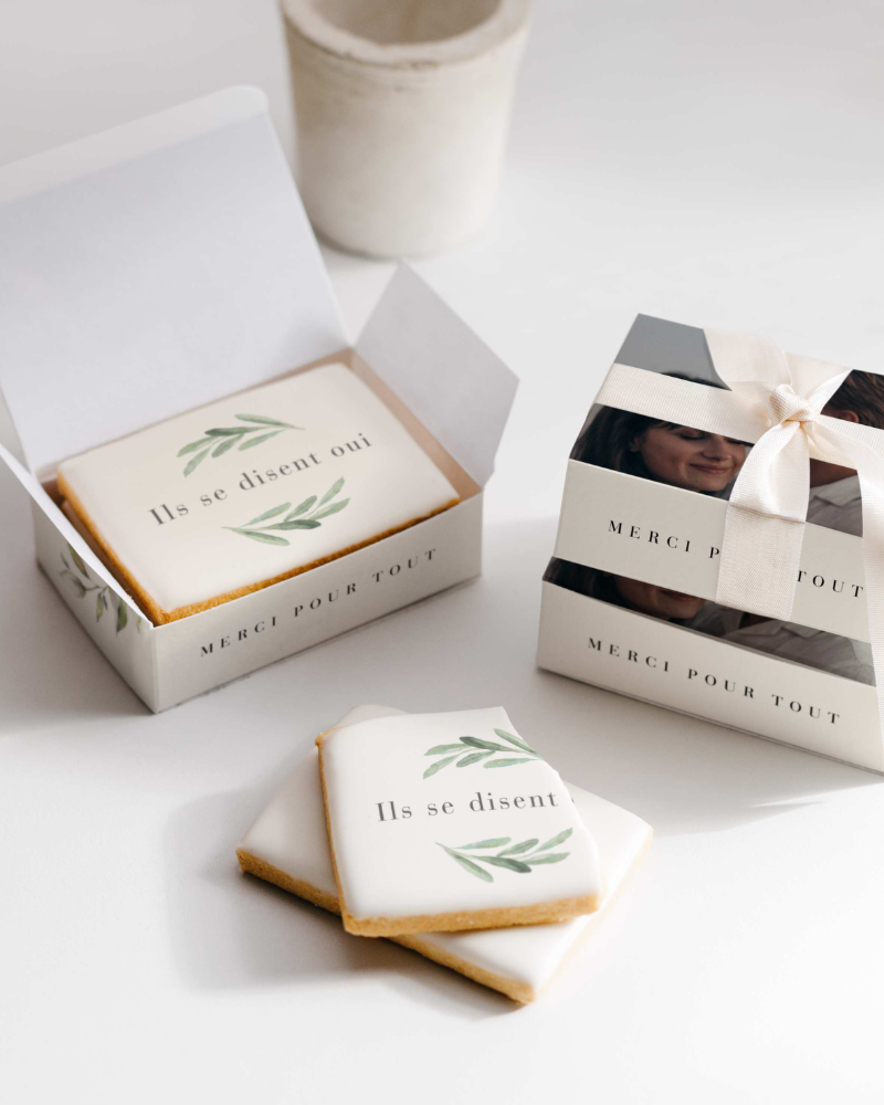 boîtes à biscuits empilées avec photographie de couple marié. Une boîte est ouverte, révélant des biscuits personnalisés avec l’inscription ils se disent oui.