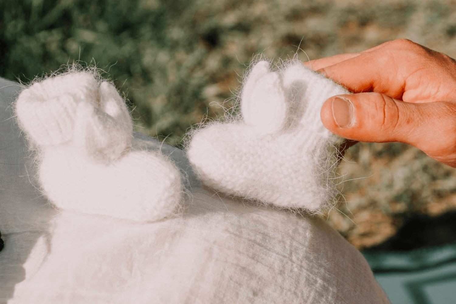 une paire de petits chaussons pour bébé de couleur blanche. 