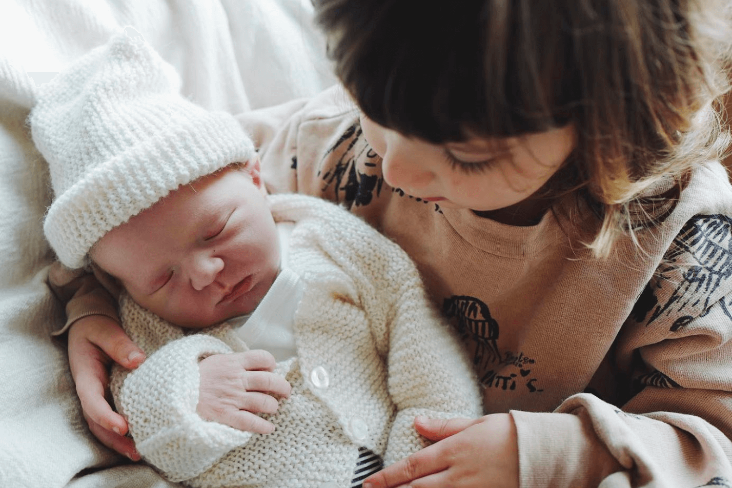 une petite fille tenant dans ses bras un nouveau-né