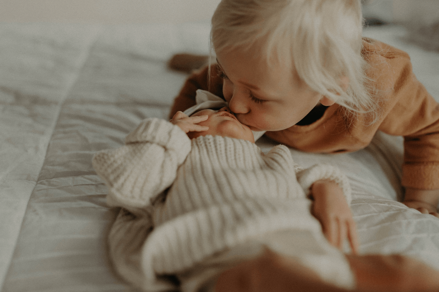 une petite fille embrassant un nouveau-né sur le front.