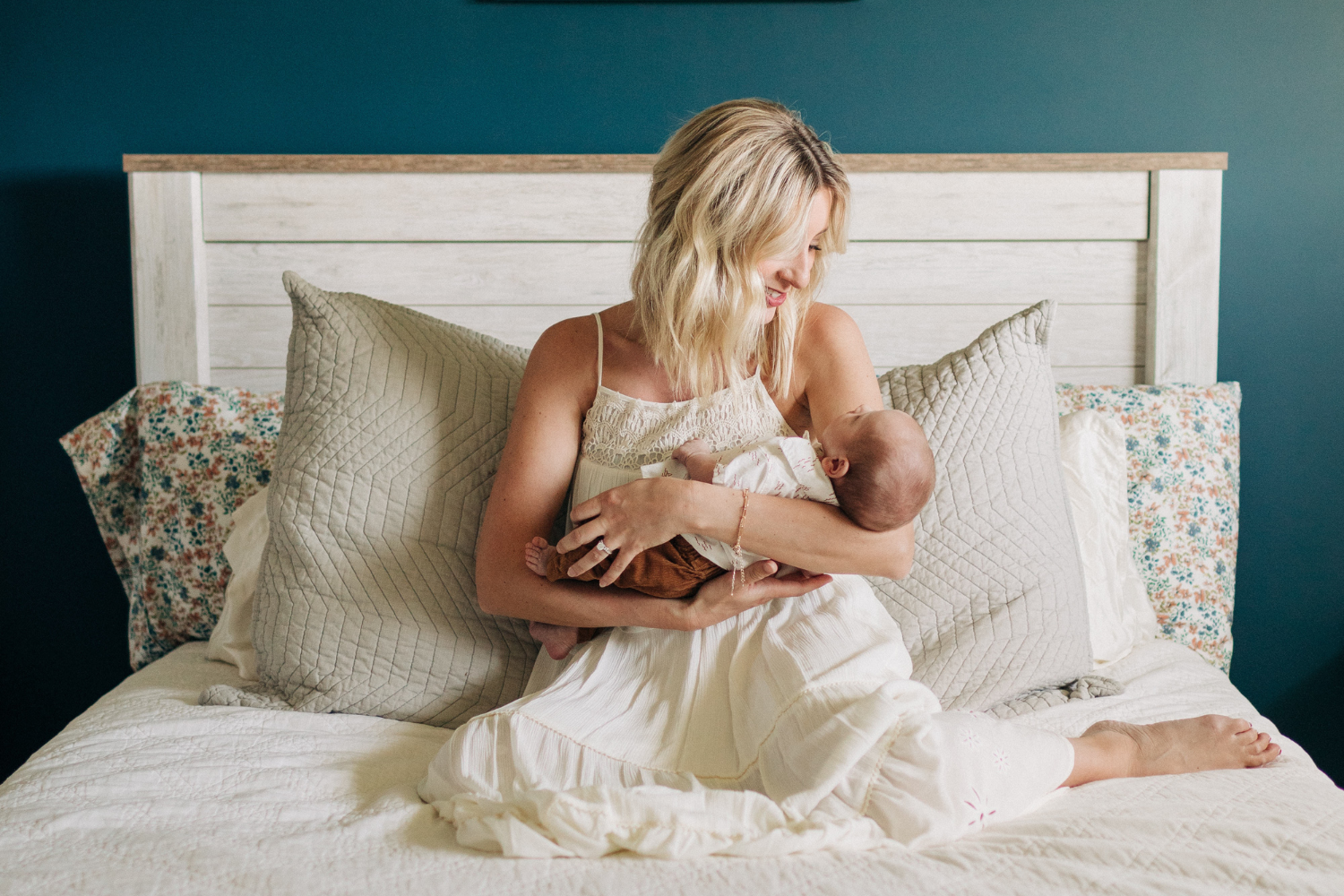 une maman assise sur son lit, tenant dans ses bras son nouveau-né.