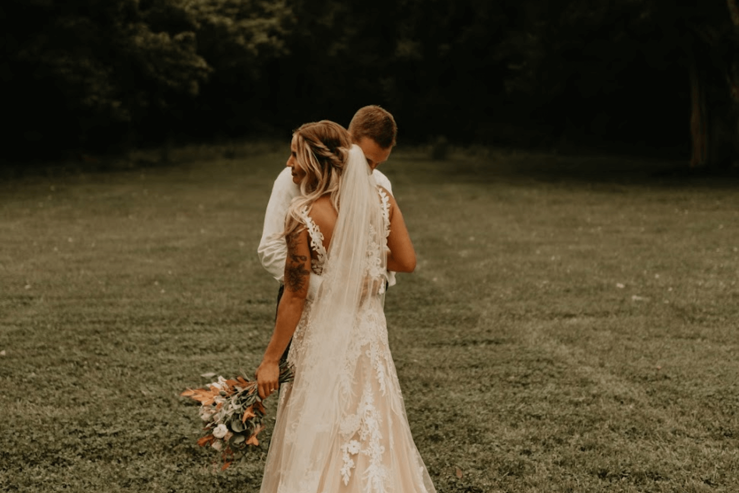 Un couple de jeunes mariés enlacés dans un parc.