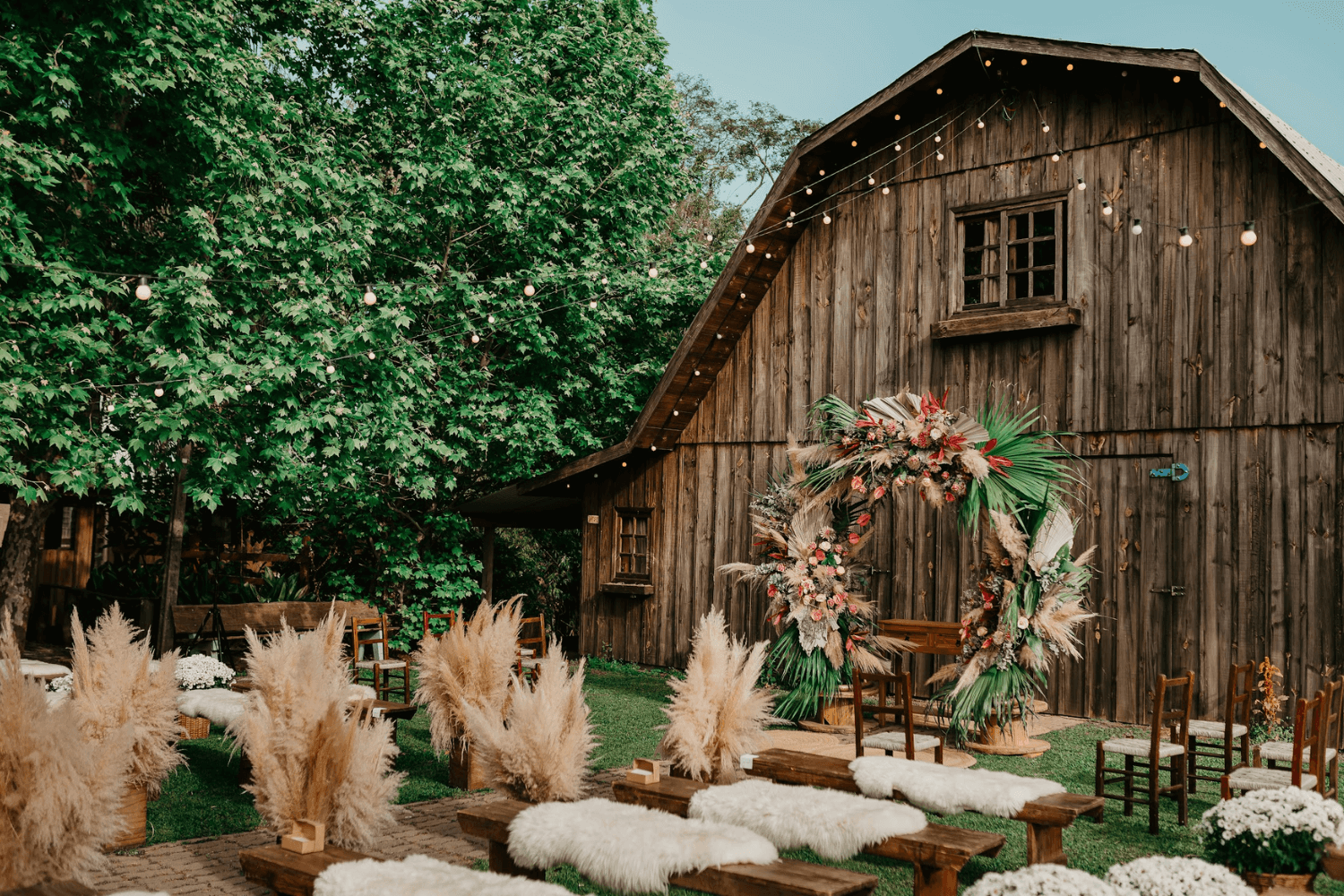 Une grange en bois avec espace de cérémonie extérieur : des bancs en bois, des herbes de la pampa…