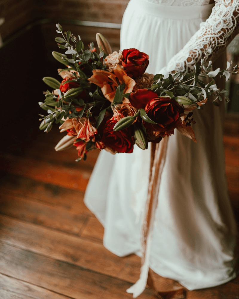 une mariée en robe bohème portant un bouquet de roses romantiques