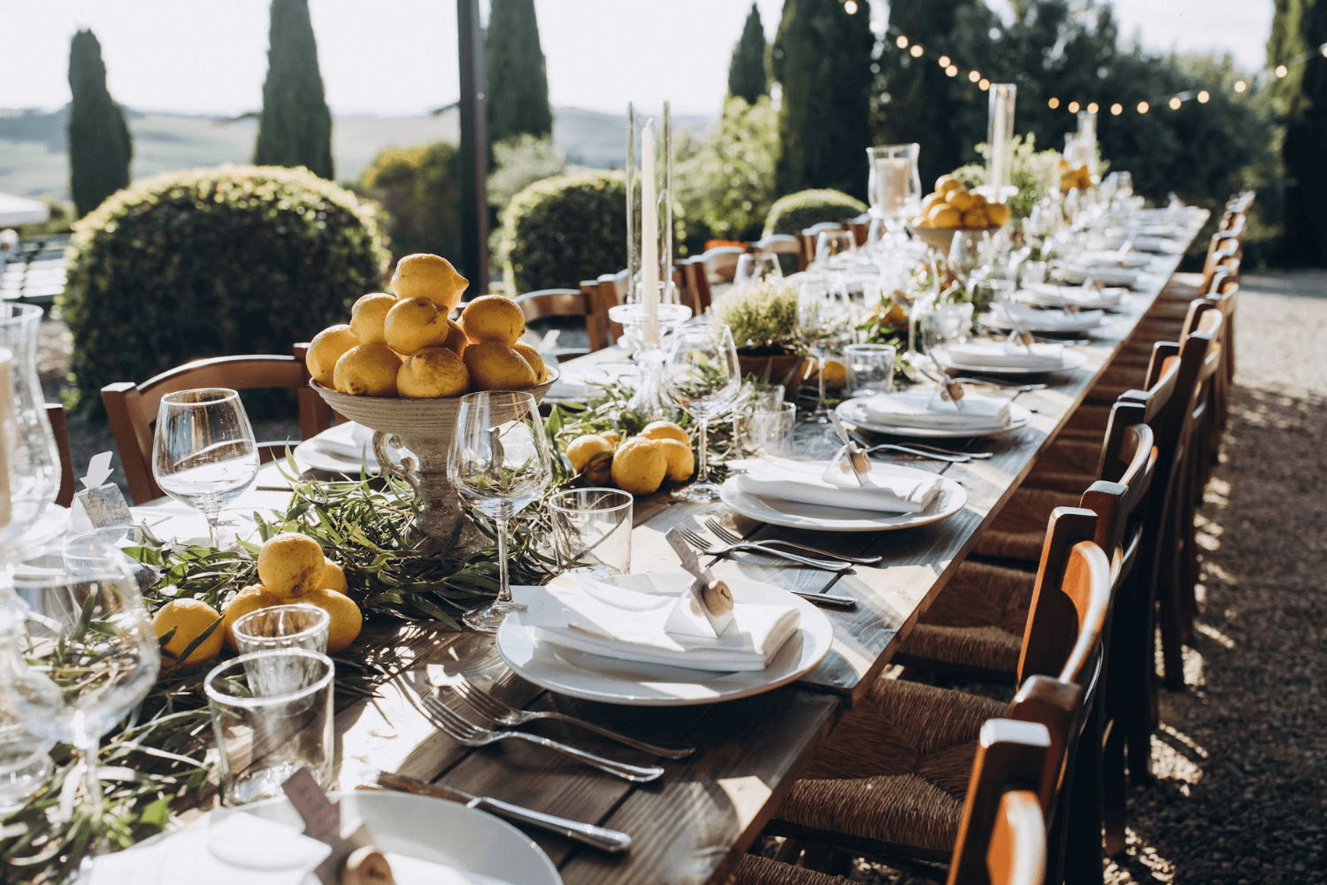 Une table de mariage d’été en bois installée à l’extérieur, garnie de citrons.