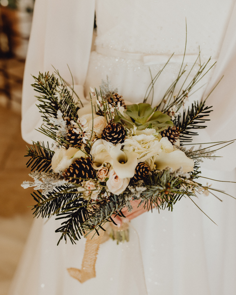 Un bouquet de mariée avec des branches de sapin et pommes de pin.