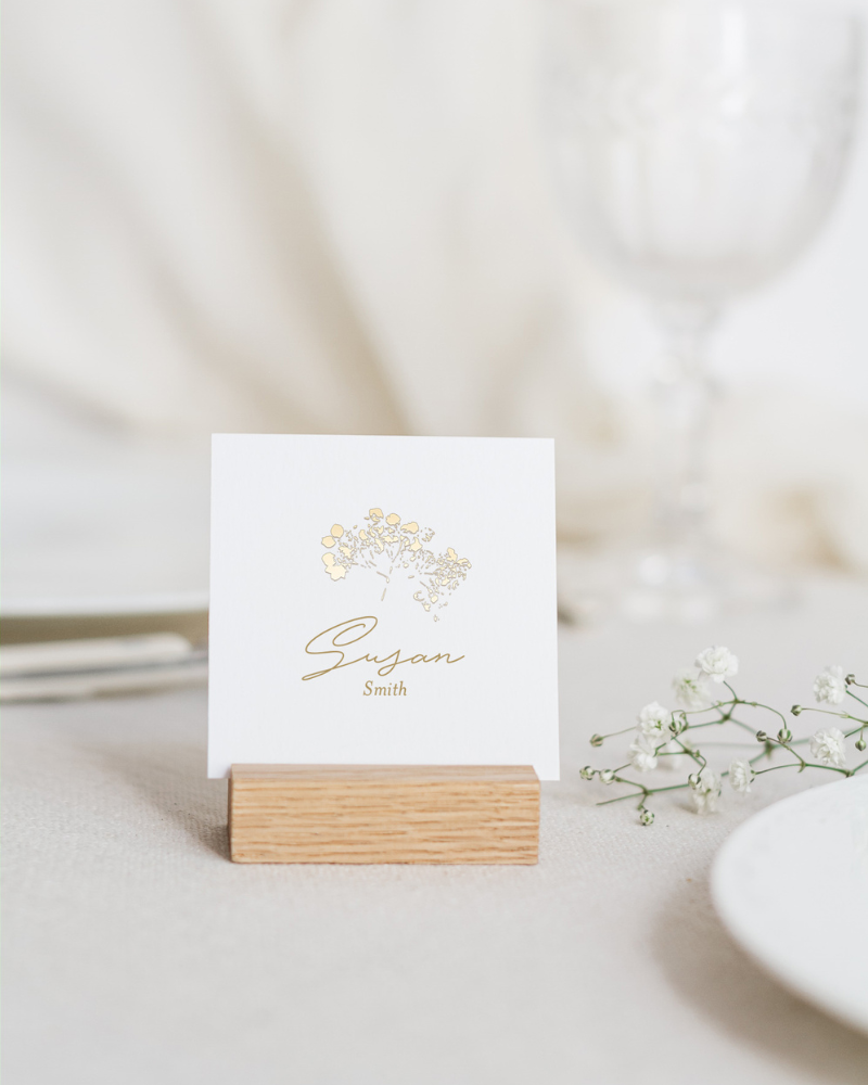 Un marque-place de mariage avec le prénom d'un invité inscrit en lettres dorées.