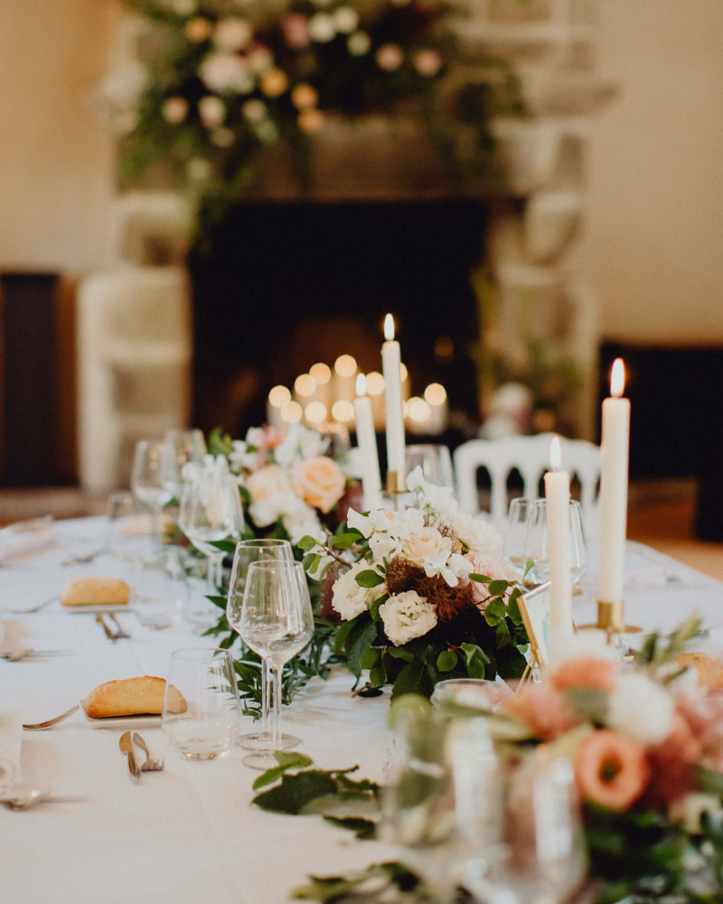 Une table de mariage avec des bouquets de fleurs et longues bougies blanches.