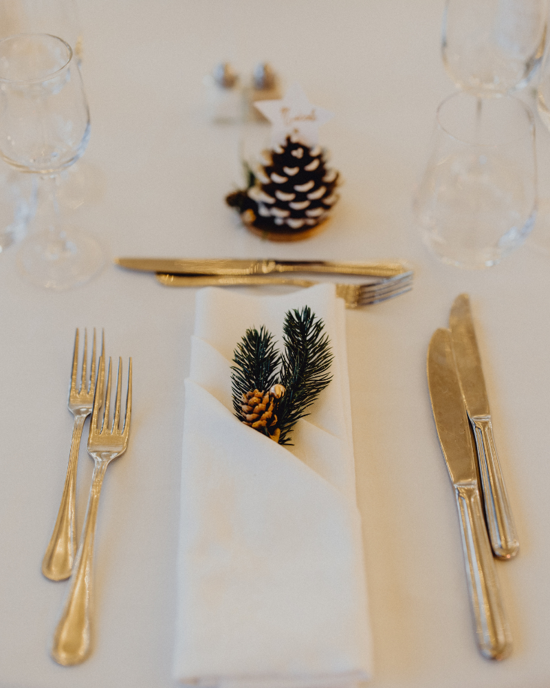 Une table de mariage avec des couverts dorés et des pommes de pin.