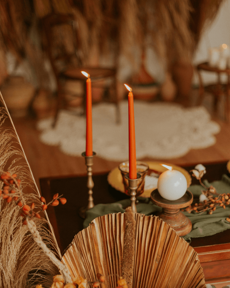 une table de mariage orientale avec de hauts bougeoirs en cuivre et bougies rouges.