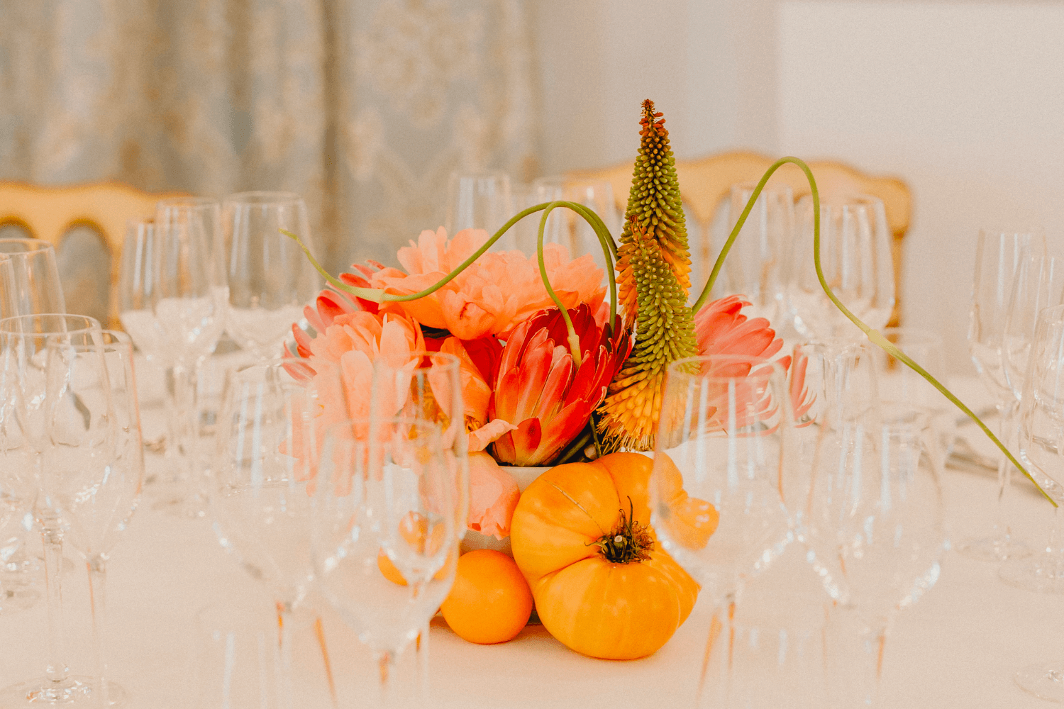 Un récipient contenant un mélange de fruits et de fleurs exotiques posé sur une table de mariage.