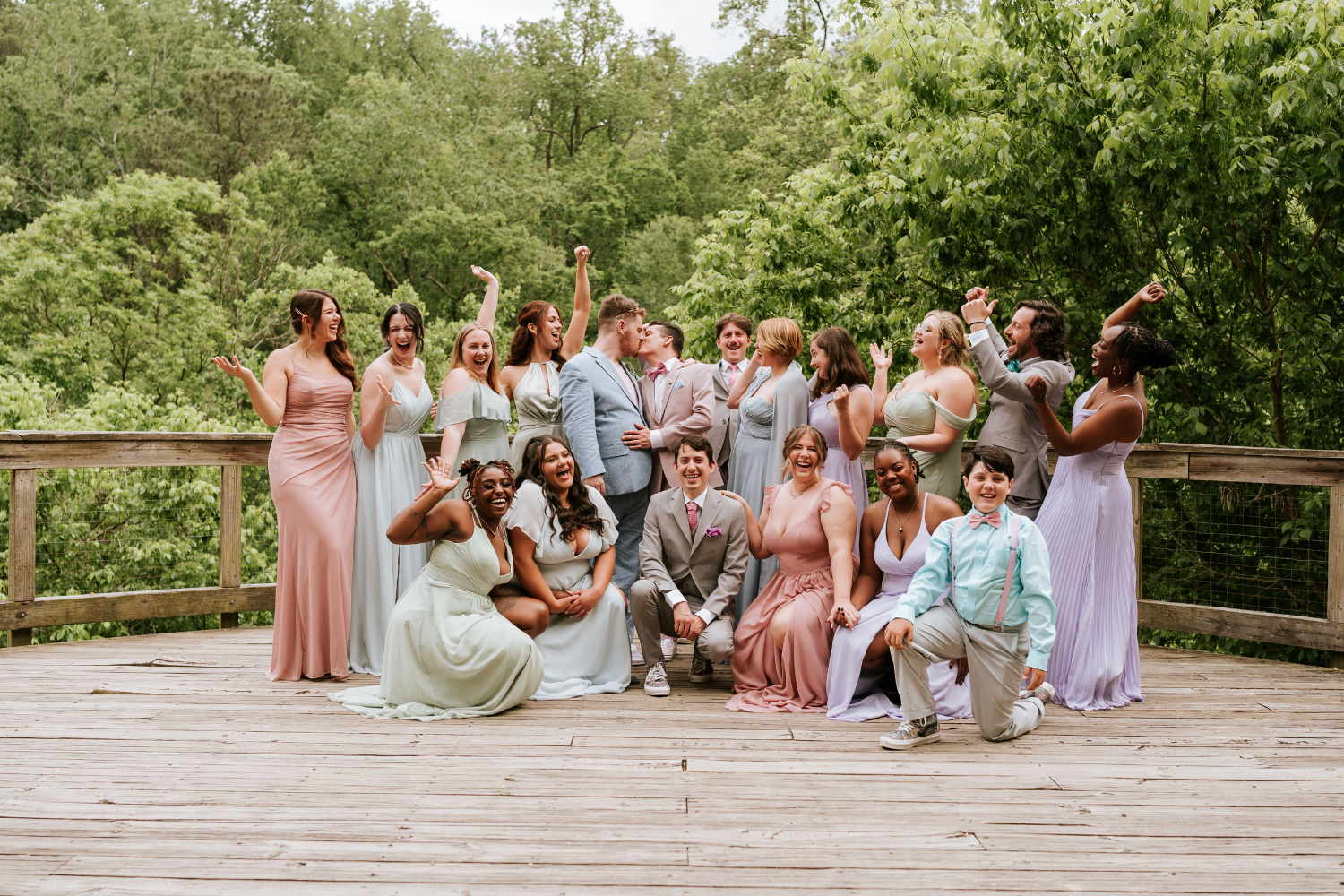 Des invités de mariage prenant la pose, vêtus de vêtements de couleurs pastel et riant aux éclats.