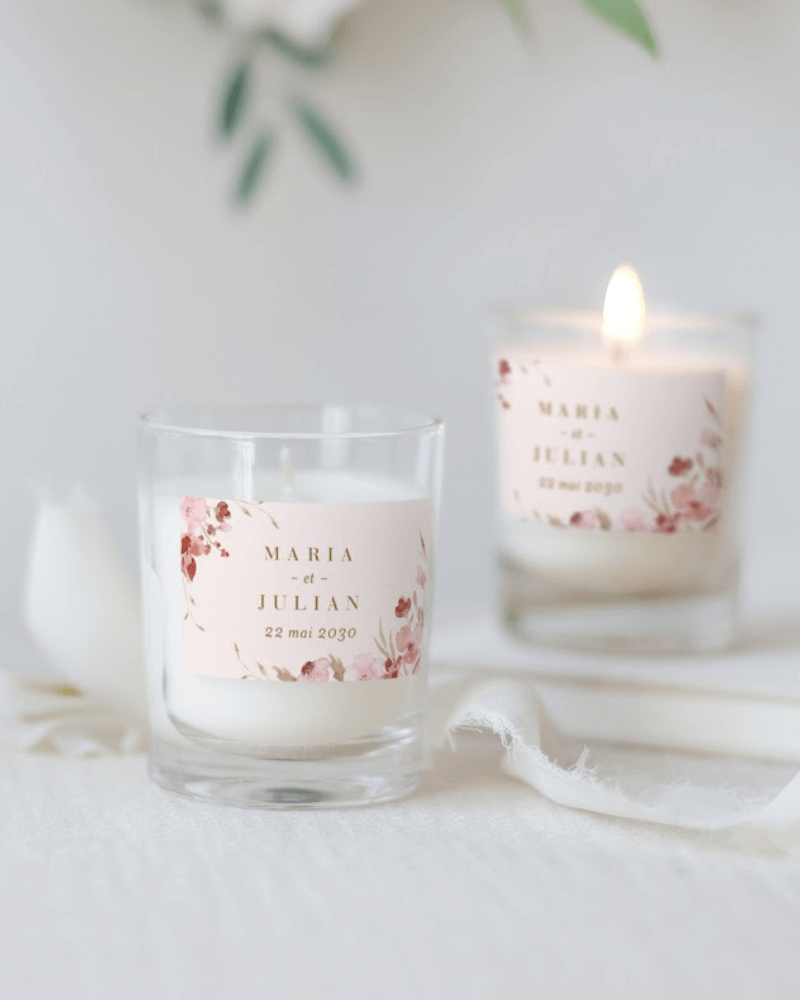 une petite bougie de mariage personnalisée, décorée d’illustrations de fleurs roses en aquarelle.