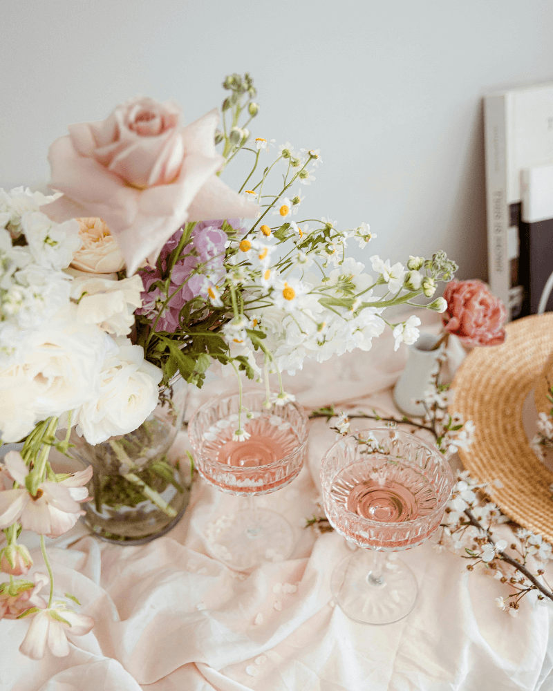 une table de mariage avec nappe rose pastel, bouquets de fleurs poétiques et verres en cristal