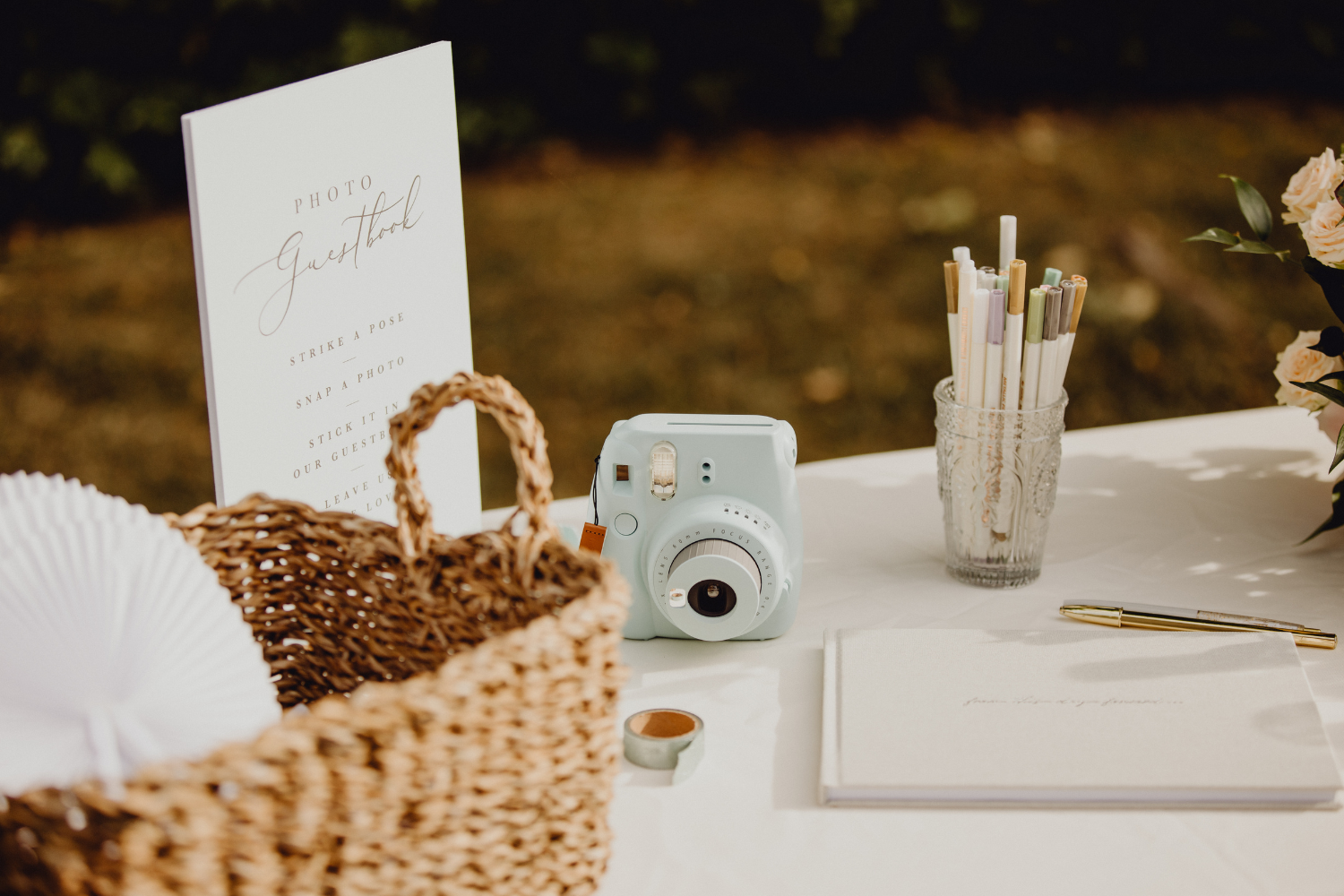 un appareil photo polaroid de mariage de couleur bleue ciel déposé aux côtés du livre d’or sur une table de mariage.