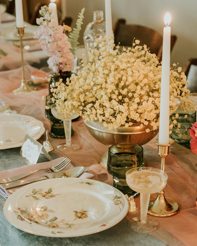 table de mariage vintage décorée d’assiettes en porcelaine illustrées de fleurs roses et de bouquets de fleurs.