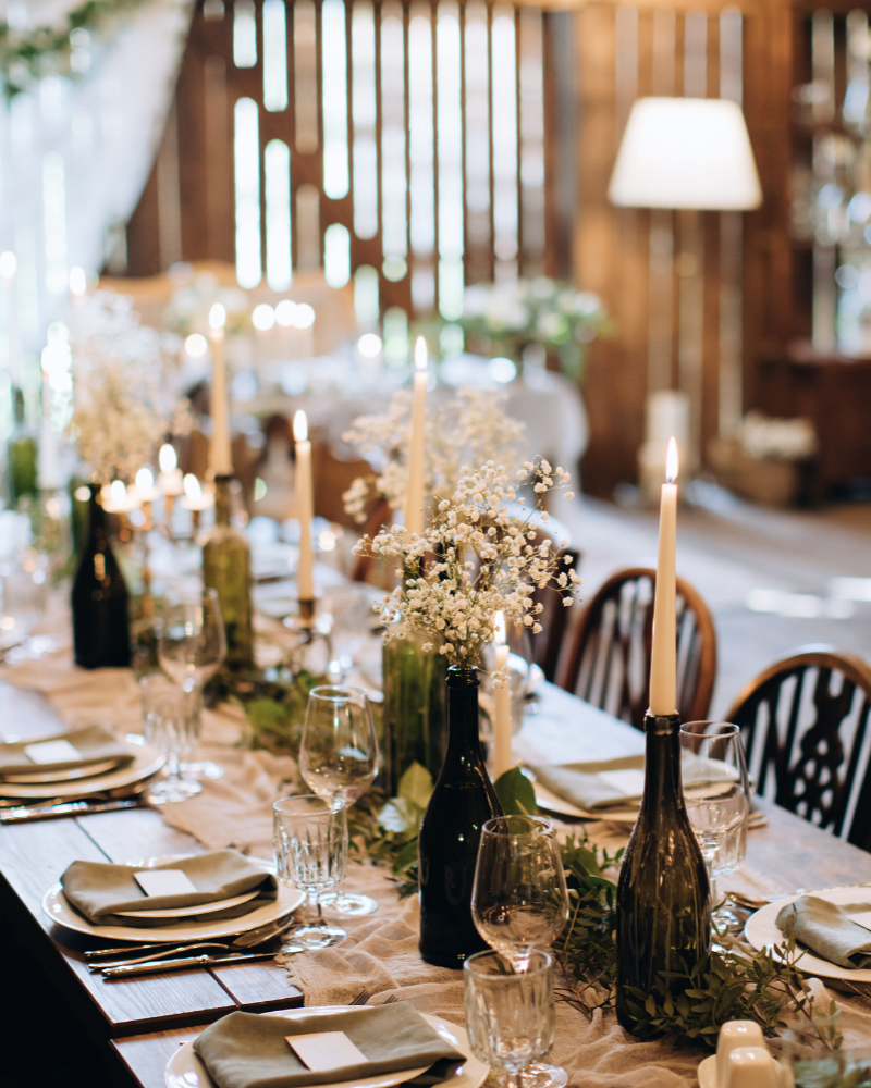 une table de mariage en bois vintage déorée de bouteilles en verre ornées de fleurs de gypsophiles