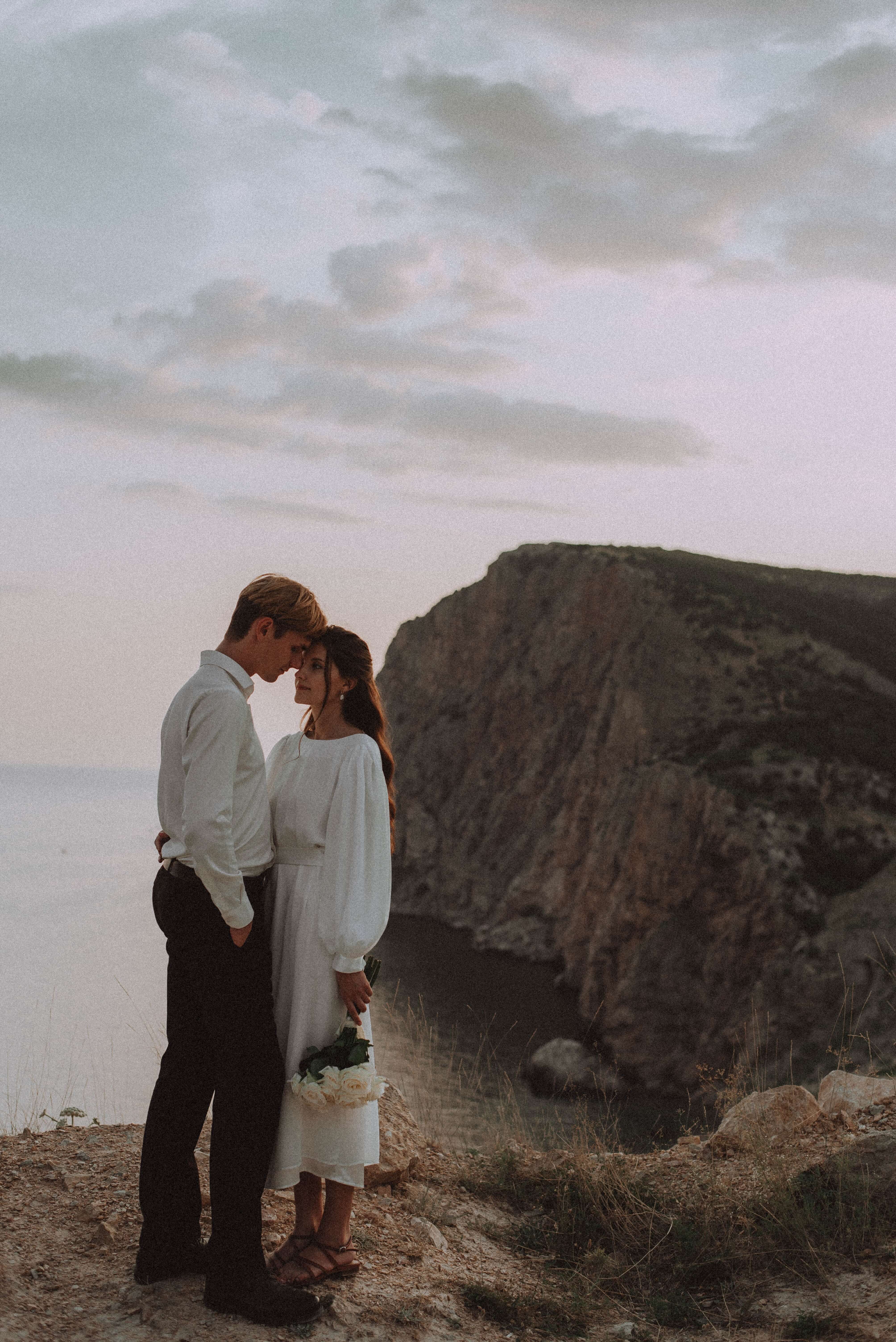 deux mariés, front contre front, se tenant au bord d’une falaise