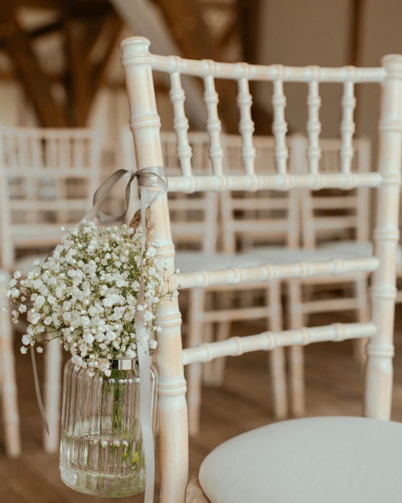 Une chaise blanche décorée d'un vase avec bouquet de gypsophiles.