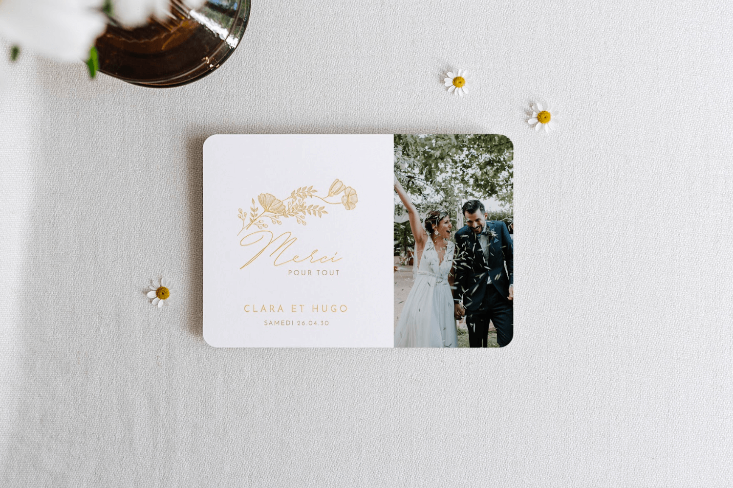 Une carte de remerciements de mariage avec photo de couple, le mot merci et une délicate illustration de fleurs inscrits en doré.