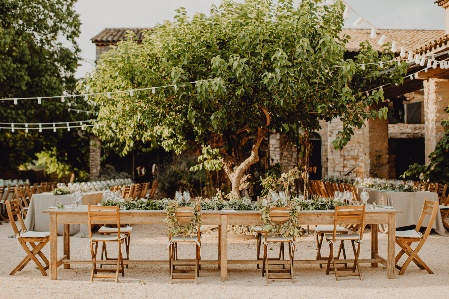 Une table de mariage champêtre en bois avec un chemin de table et des décorations végétales.