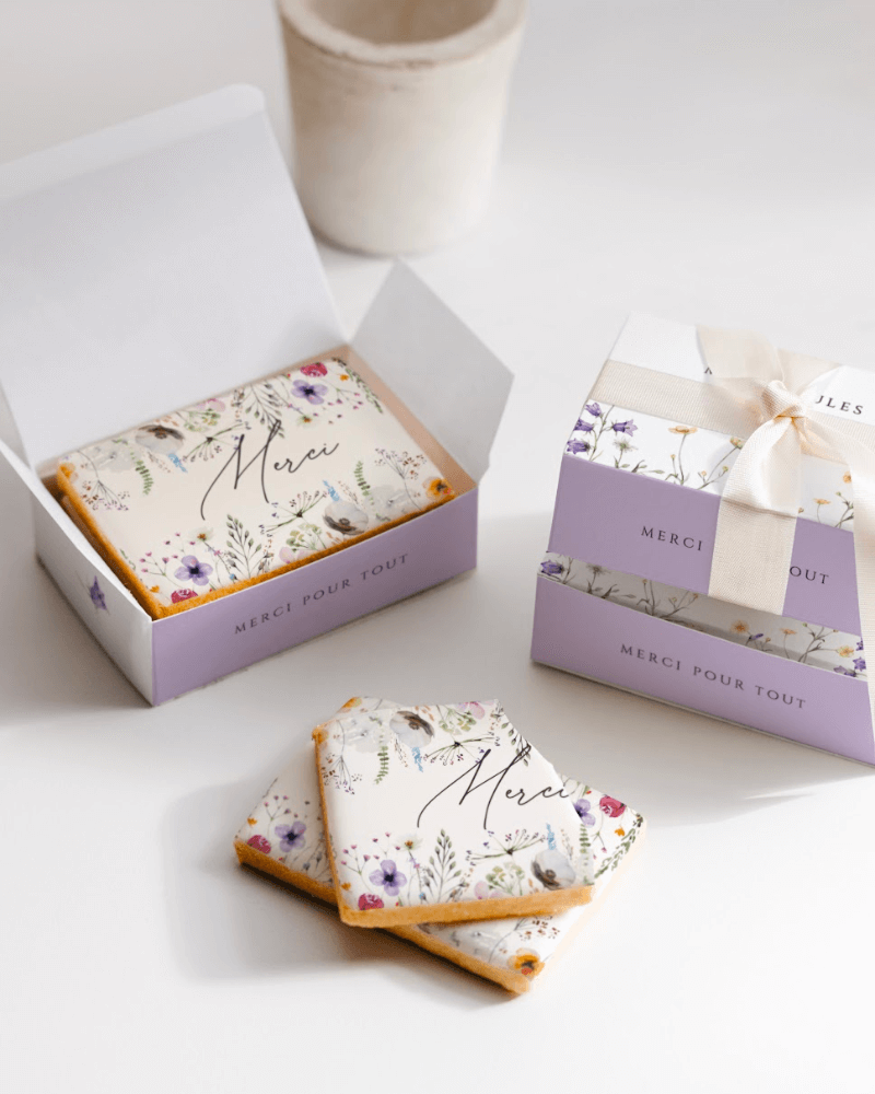 Une boîte à biscuits personnalisée cotton bird, avec de jolies illustrations fleuries.  à l'intérieur, on aperçoit des biscuits, aussi personnalisés et illustrés de fleurs.