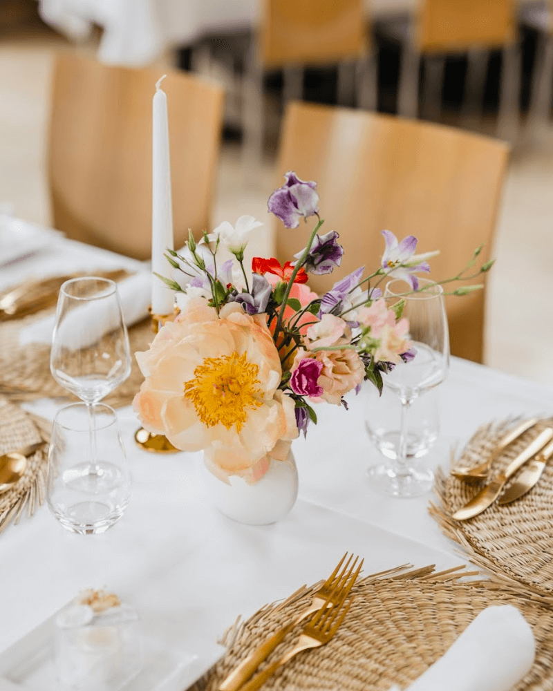 table de mariage blanche avec sous-plats en osier et bouquets de fleurs colorées