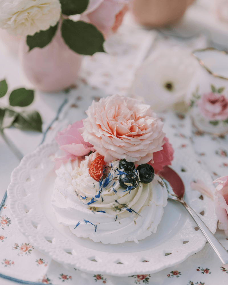 meringue déposée sur une assiette blanche décorée de fleurs et de fruits.
