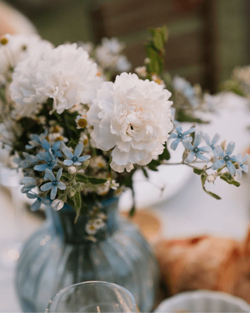 un bouquet de fleurs bleues et blanches sur une table de mariage